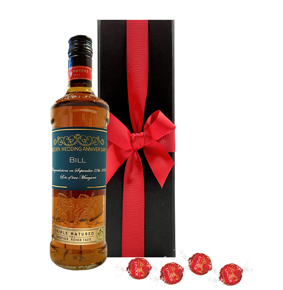 Personalised blended Scotch whisky with a custom label beside a black gift box, with Swiss chocolate truffles in front