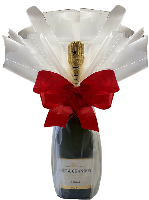 Champagne bottle in a crisp white ruffle gift wrap framing the neck, tied with a large red satin bow.