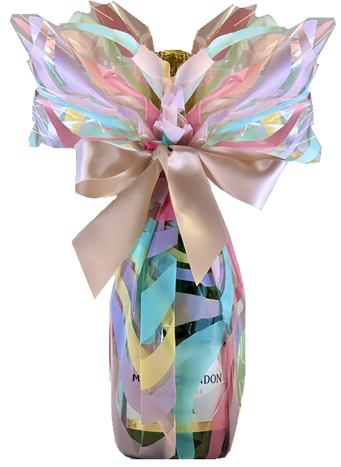 Champagne bottle in a shimmering pastel gift wrap of pink, blue and lilac, tied with a big blush satin bow.