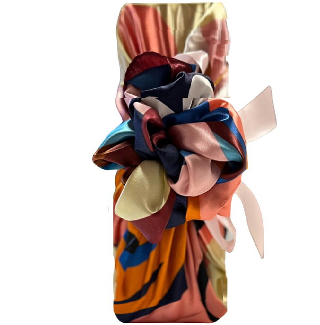 Champagne bottle wrapped Furoshiki-style in a bright multicoloured silky scarf, hand-tied in a bow