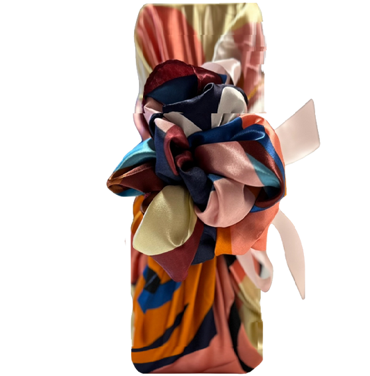 Champagne bottle wrapped Furoshiki-style in a bright multicoloured silky scarf, hand-tied in a bow