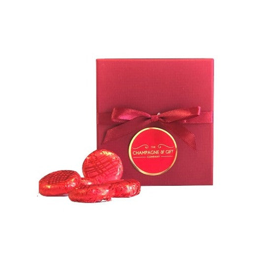 Red gift box tied with red ribbon with red foil-wrapped strawberry chocolate creams