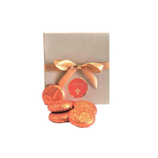 Gold gift box tied with gold ribbon with orange foil-wrapped chocolate creams