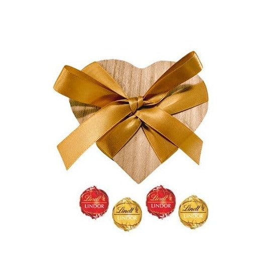 Wooden heart trinket box tied with gold ribbon with four foil-wrapped Swiss truffles
