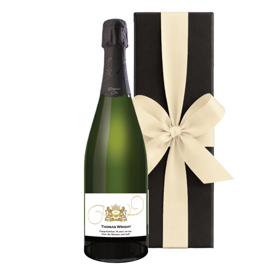 Champagne branded with logo. Premier Cru bottle with a company crest label beside a black gift box with a cream bow.