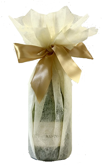 Champagne bottle hand-wrapped in a soft cream gift wrap, gathered at the neck with a golden satin bow.