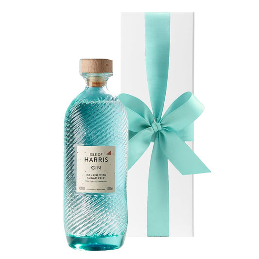 Isle of Harris Gin in its rippled sea-glass bottle beside a white gift box with a large bow