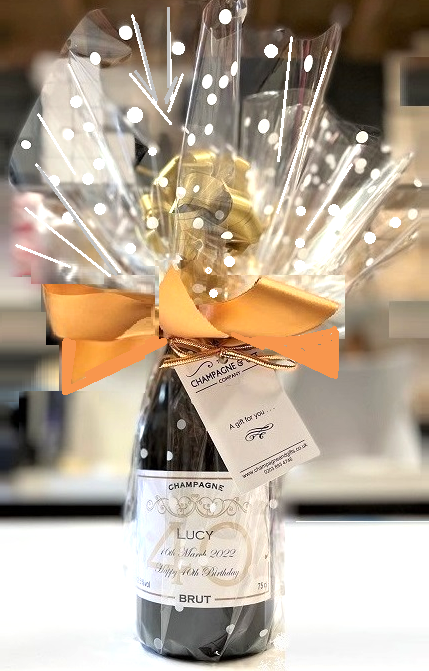 Champagne bottle in a sparkling clear ruffle gift wrap fanned around the neck and tied with a big bow.